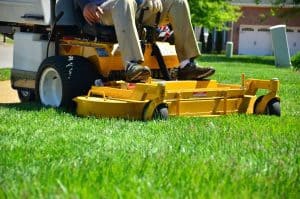 Yellow rider mower cutting a client's side yard.